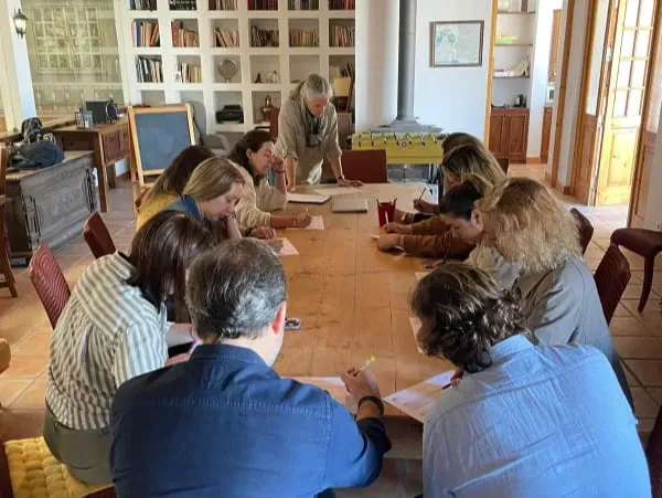 O grupo sentado à volta de uma mesa faz a autoavaliação das soft skills numa sala acolhedora.
