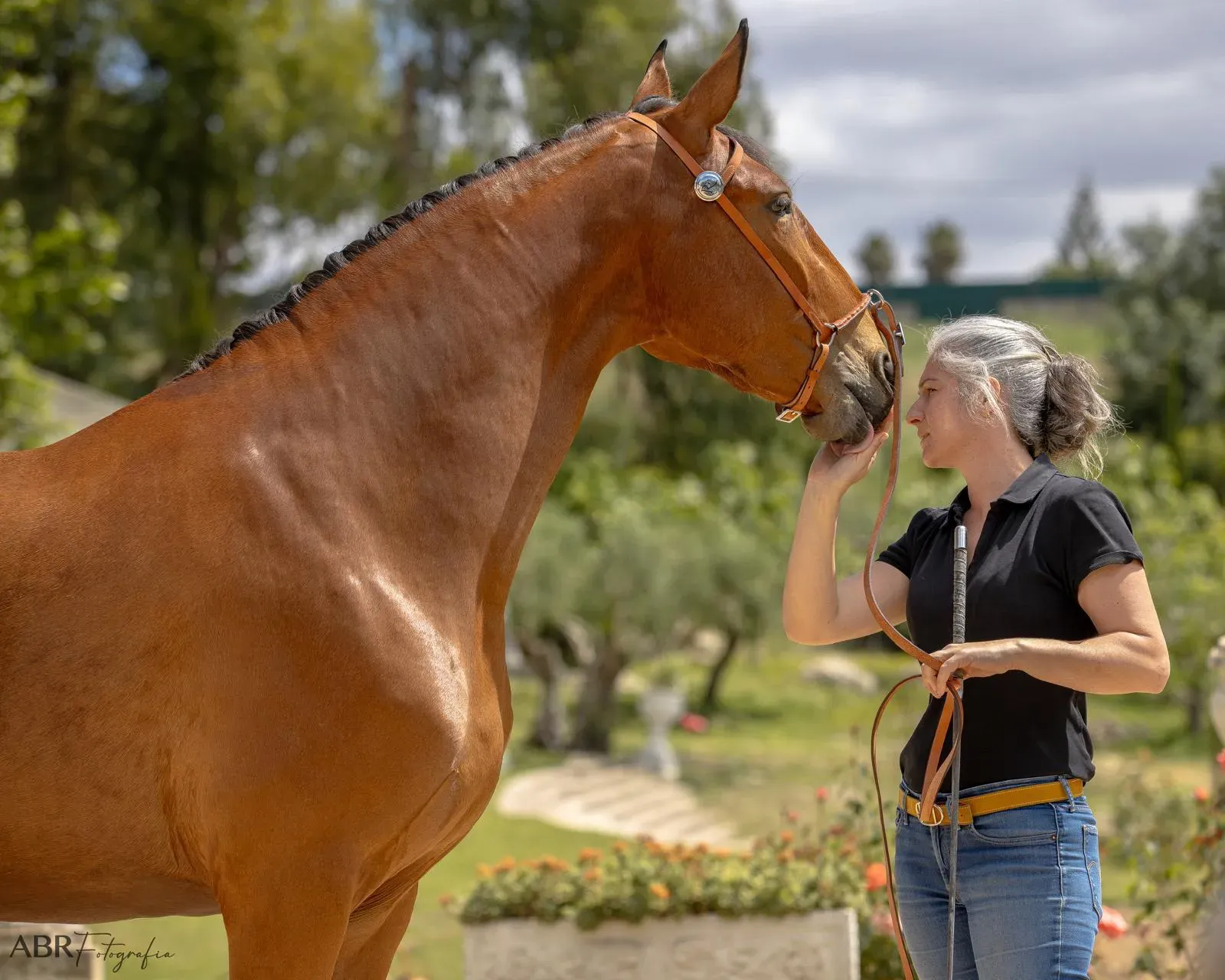 Léa Forge partilha um momento de cumplicidade com um cavalo castanho ao ar livre.