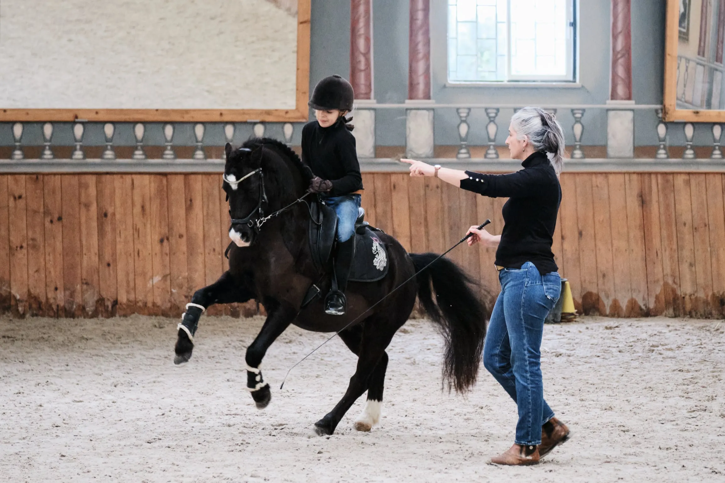 Jeune cavalière et son poney en cours avec la coach, cherchant l’équilibre de la pirouette au galop