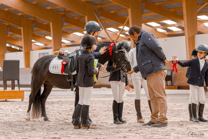 Poney à la remise des prix, entouré de jeunes cavalières